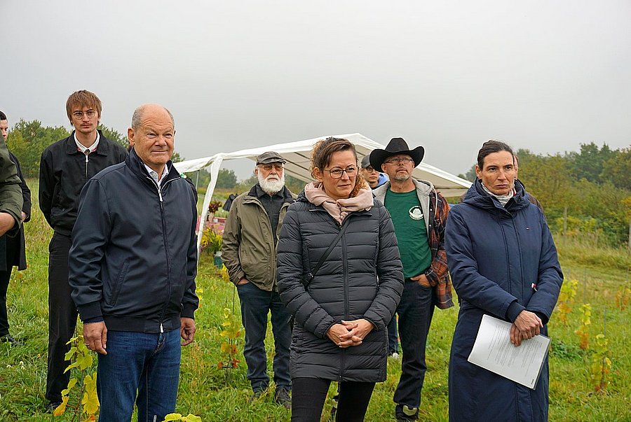 Dr. Olivia Kummel (re), Geschäftsführerin des LPV Potsdamer Kulturlandschaft, erläutert Altkanzler Olaf Scholz MdB (li) und Brandenburgs Landwirtschaftsministerin Hanka Mittelstädt MdL (Mitte) die Tätigkeit der Kooperative des LPV.