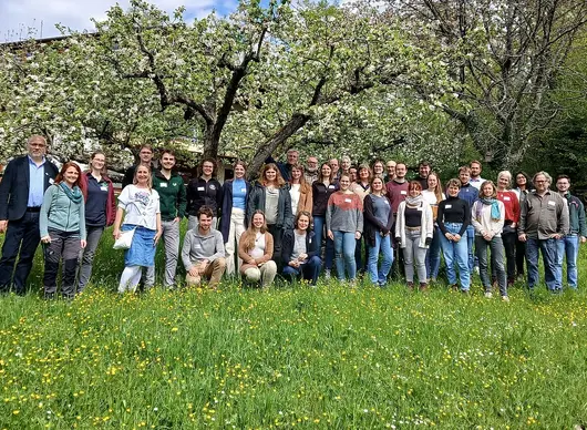Etwa 40 Landschaftspflegende vor blühenden Streuobstbäumen